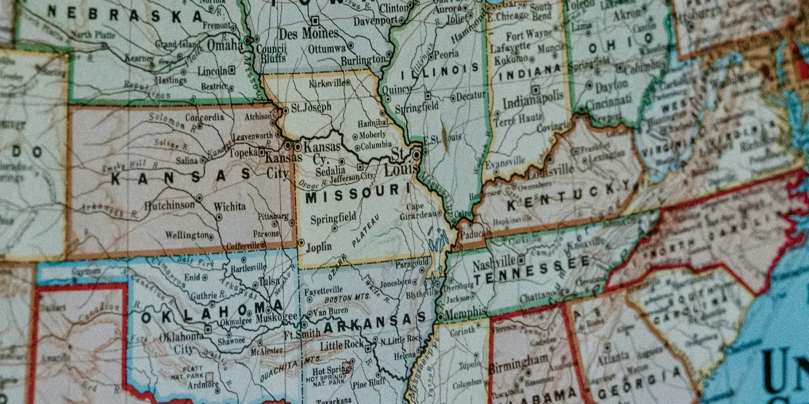 A close-up of a printed United States map showing the central states, including Kansas, Missouri, Oklahoma, Arkansas, and Tennessee, with state borders and city names.
