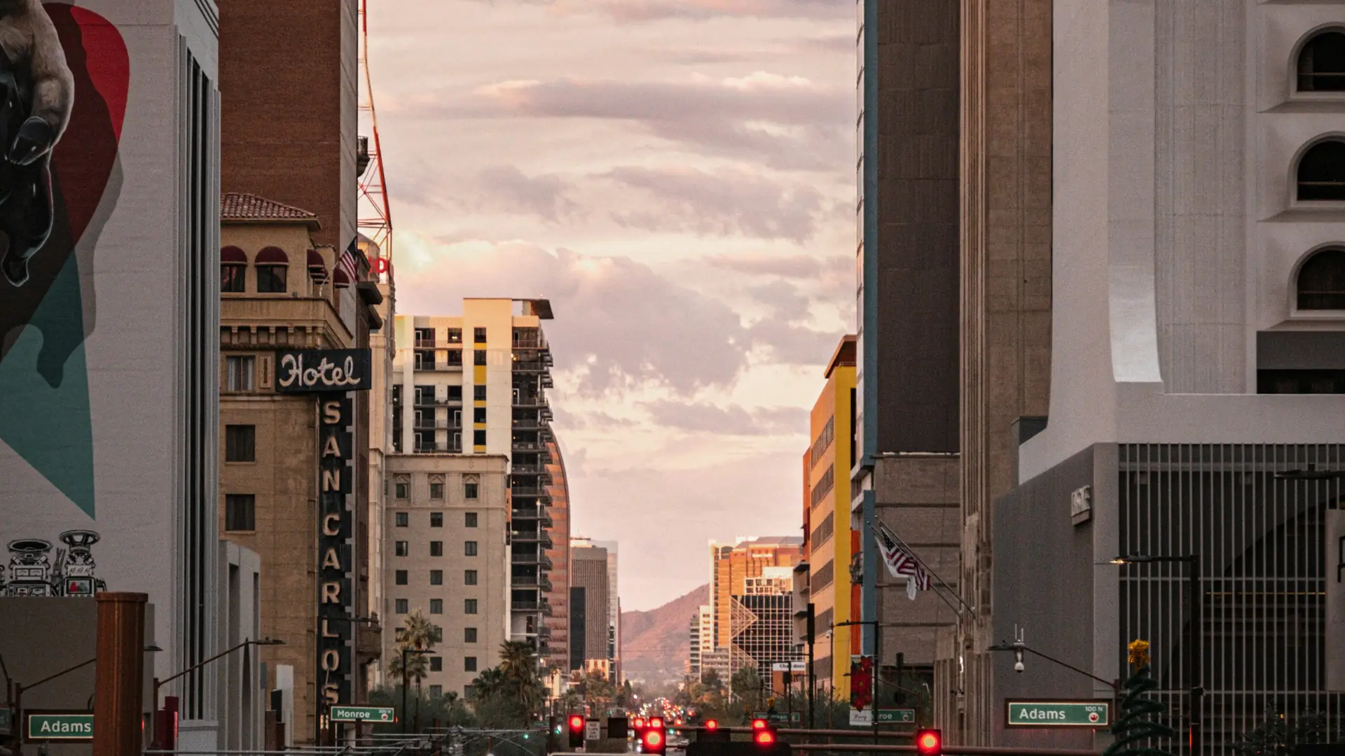 A downtown Phoenix street at sunset with mountains in the distance