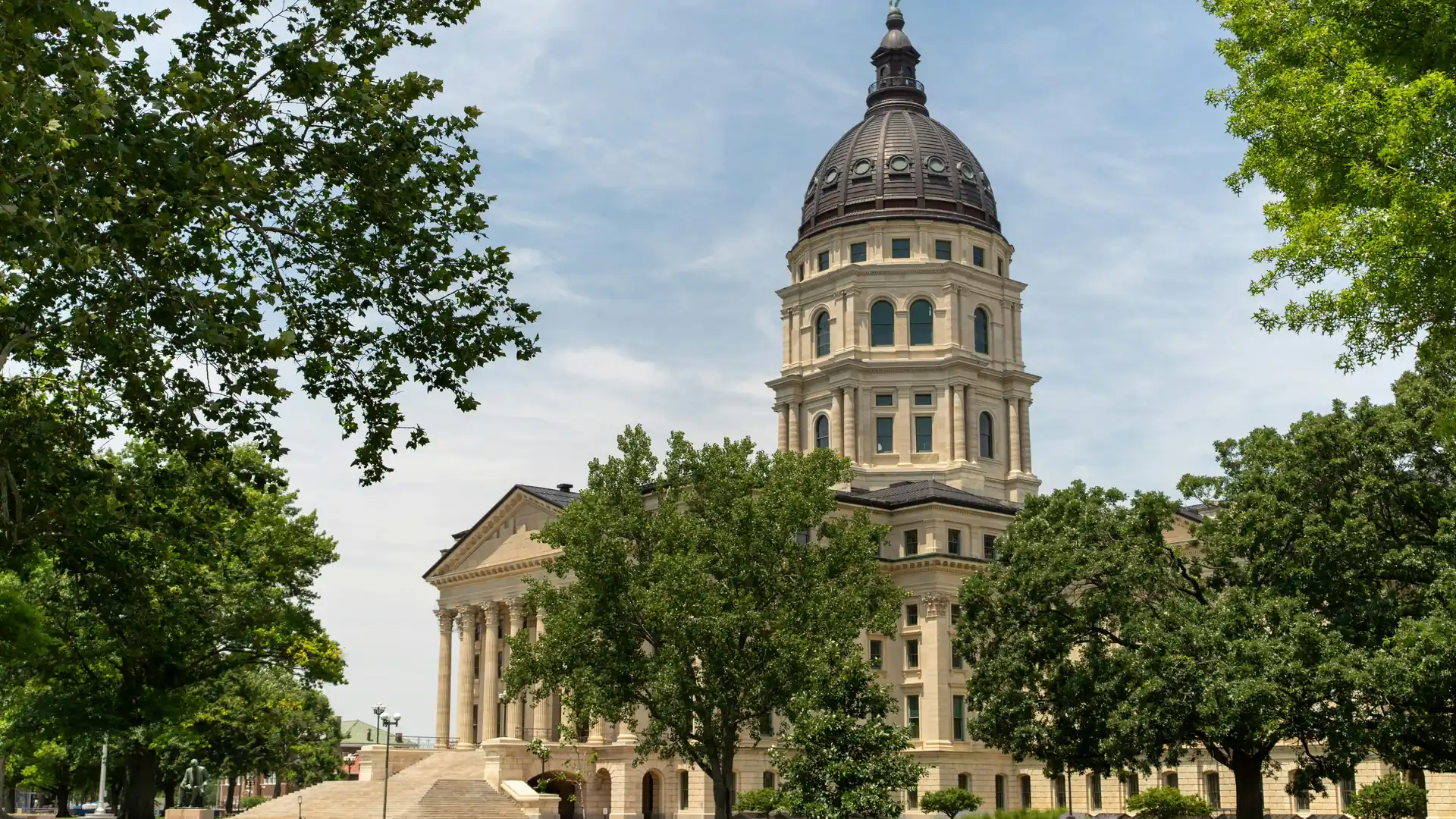 The Kansas State Capitol dome in Topeka framed by summer trees